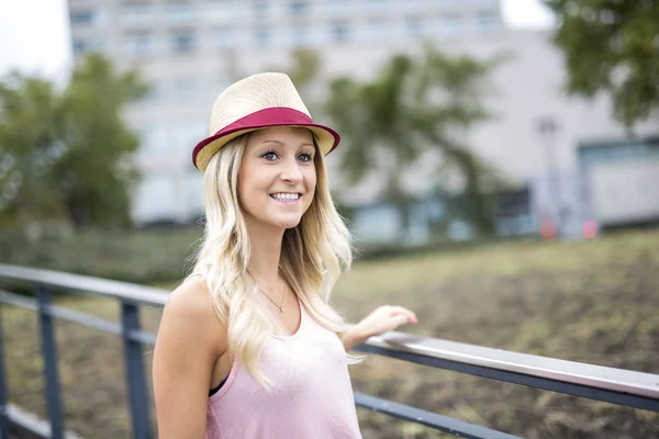 Schönes und junges Mädchen mit Hut, das in der Abendstadt spaziert — Stockfoto