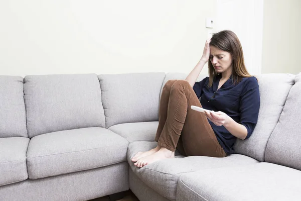 Girl sitting on a couch at home while reading the results of her recent pregnancy test — Stock Photo, Image