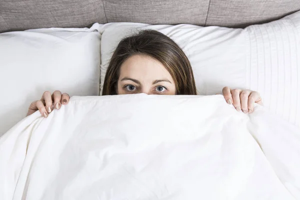 Unga sovande kvinnan i sovrummet hemma klädd i vitt — Stockfoto