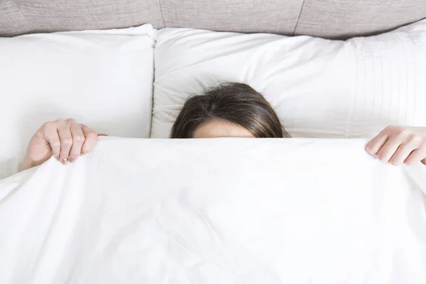 Unga sovande kvinnan i sovrummet hemma klädd i vitt — Stockfoto