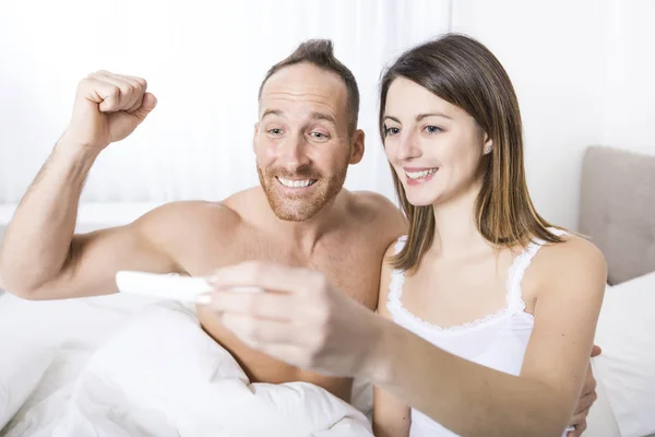 쾌활 한 부부는 임신의 결과 알아내는 테스트 침대에 앉아 — 스톡 사진