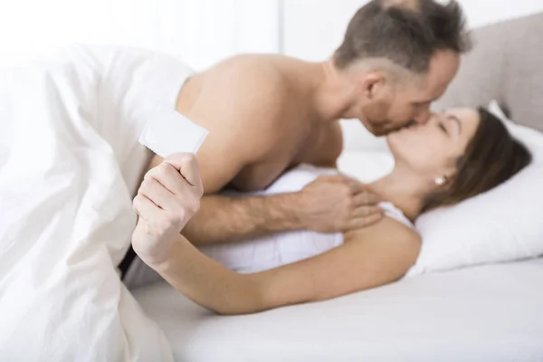 콘돔과 함께 침대에 젊은 매력적인 부부 — 스톡 사진
