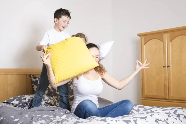 Junge Mutter und Kinder bei morgendlichen Yoga-Übungen im Bett — Stockfoto