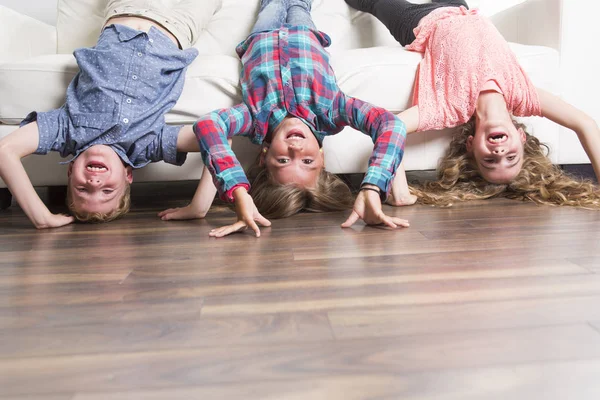 Drie childs ondersteboven opleggen op een witte Bank thuis — Stockfoto