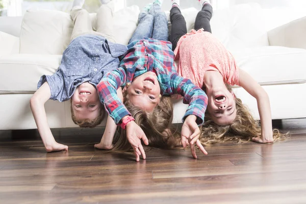 Drie childs ondersteboven opleggen op een witte Bank thuis — Stockfoto