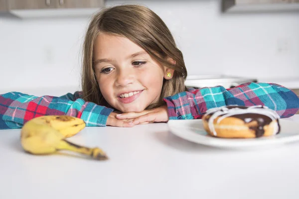 Kind kiezen tussen gezonde groenten en lekkere snoepjes — Stockfoto