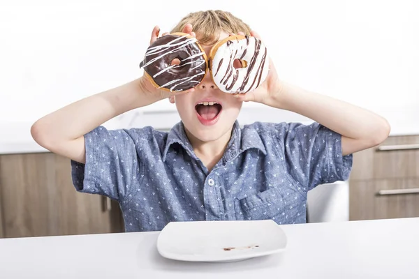 Barn leker med donuts i hennes händer att sätta dem på hennes ansikte — Stockfoto