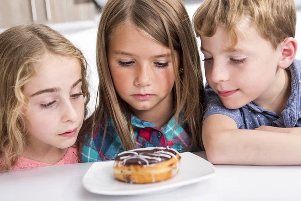 Jong kind zit op tabel horloge Donut — Stockfoto