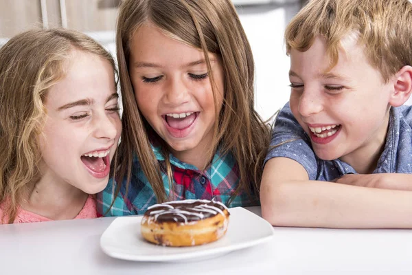 젊은 자식 테이블에 앉아 시계 도넛 — 스톡 사진