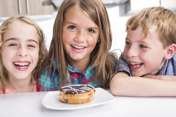 Jong kind zit op tabel horloge Donut — Stockfoto