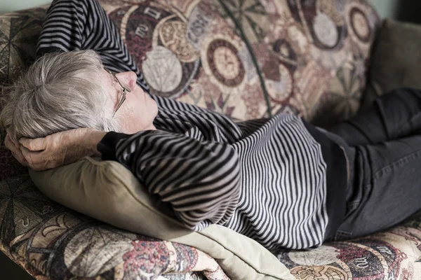 Senior mulher relaxante no sofá — Fotografia de Stock
