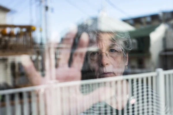 Senior woman looking out through a window like depress — Stock Photo, Image