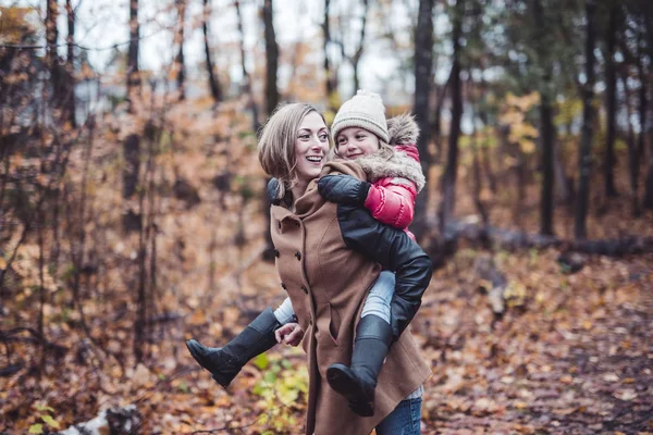 一个微笑的年轻女子，与一个小女孩在秋天的肖像 — 图库照片