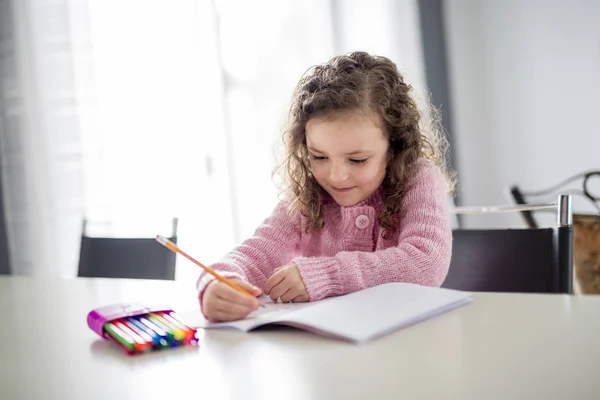 Дівчина пише з ручкою за столом — стокове фото