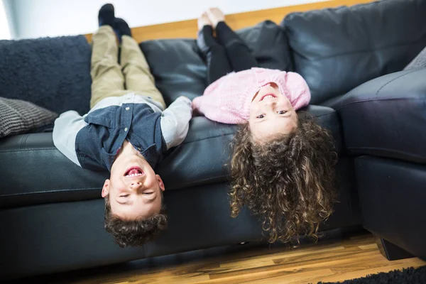 Menina bonita e menino estão deitados de costas no sofá — Fotografia de Stock