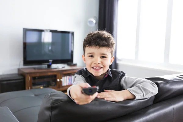 Liten pojke tittar på Tv liggande i vardagsrummet — Stockfoto