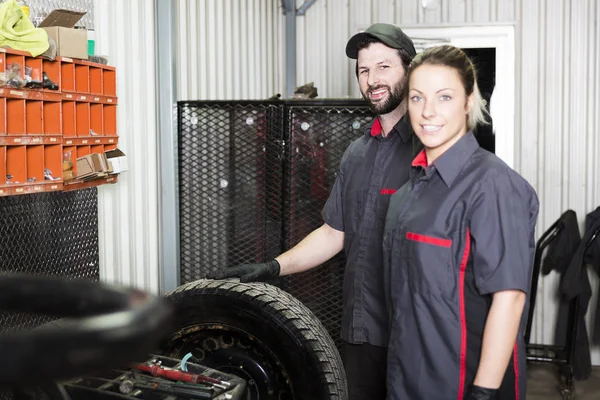 Monteur vrouw en mannen aan het werk van ploeg in zijn winkel — Stockfoto