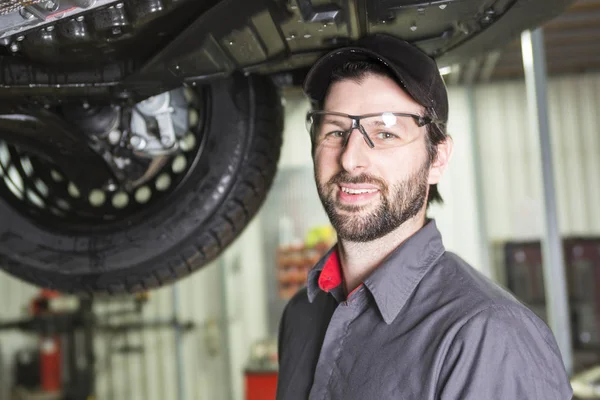 Mechanic working on car in his shop — Stock Photo, Image