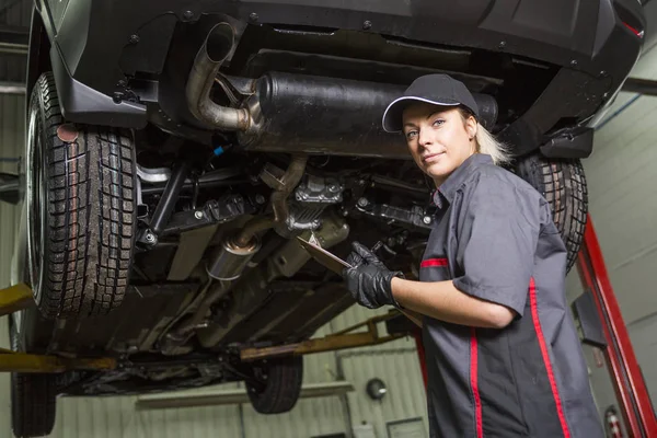 Mechanik žena pracuje na autě v jeho obchodě — Stock fotografie