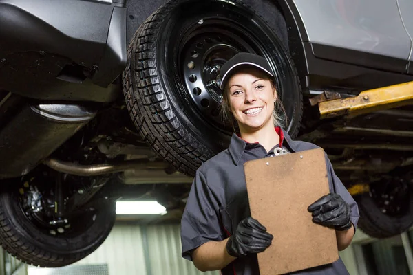 Monteur vrouw werken aan auto in zijn winkel — Stockfoto