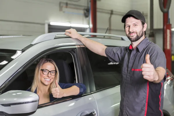 Автомеханик и женщина-клиент в гараже — стоковое фото