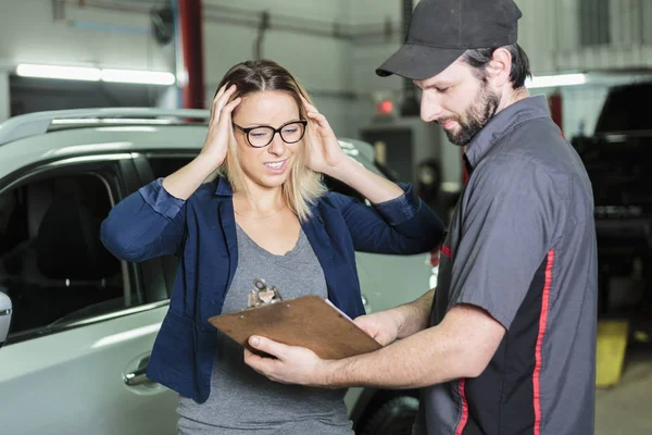 Автомеханик и женщина-клиент в гараже — стоковое фото