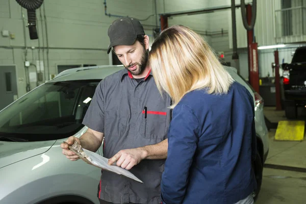 Mecánico de automóviles y cliente femenino en el garaje — Foto de Stock