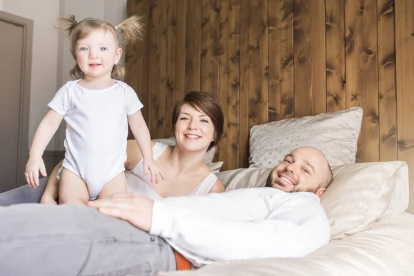 Belle mère et beau père avec bébé fille couché sur la chambre — Photo