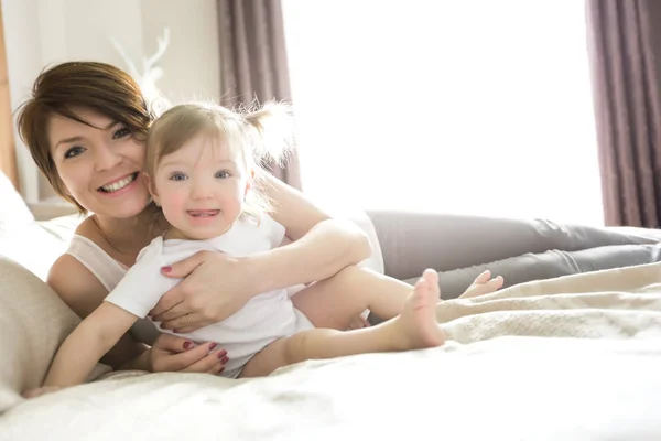 Jovem mãe feliz com bebê na cama — Fotografia de Stock