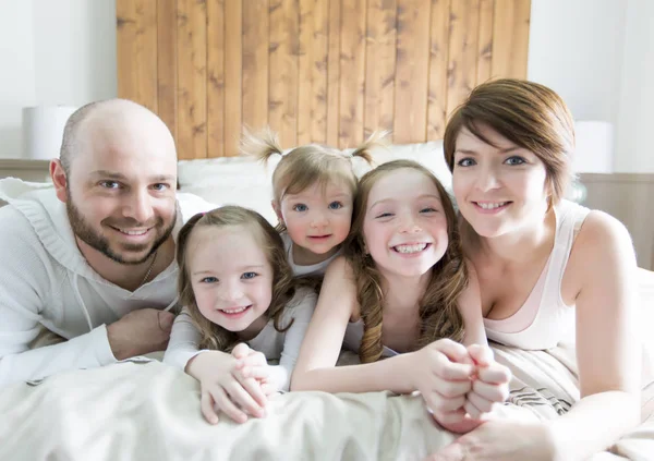 Jonge gelukkige familie van vijf op slaapkamer — Stockfoto