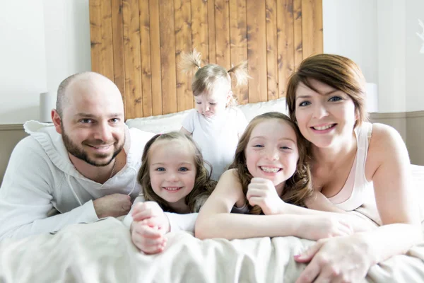Jonge gelukkige familie van vijf op slaapkamer — Stockfoto