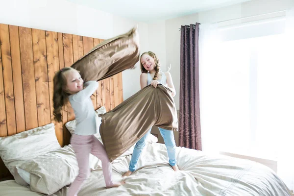 Portrait kids fighting with pillows in bed