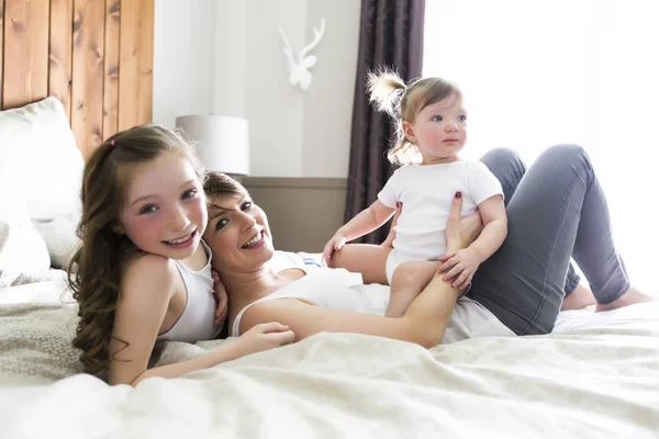 Mother and two children in the bedroom on the bed — Stock Photo, Image