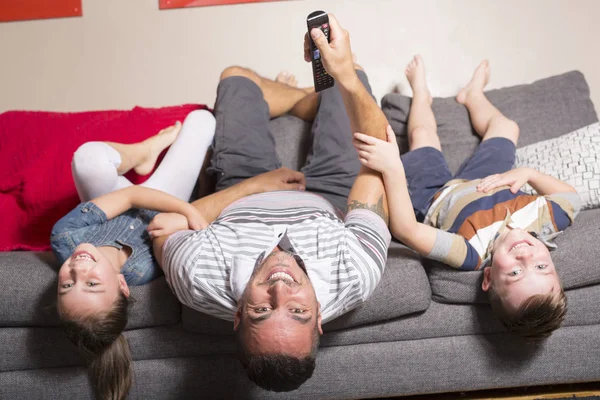 Familie ondersteboven liggend op de Bank — Stockfoto