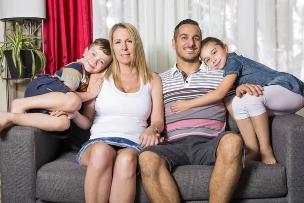 Família de quatro pessoas no sofá da sala de estar — Fotografia de Stock