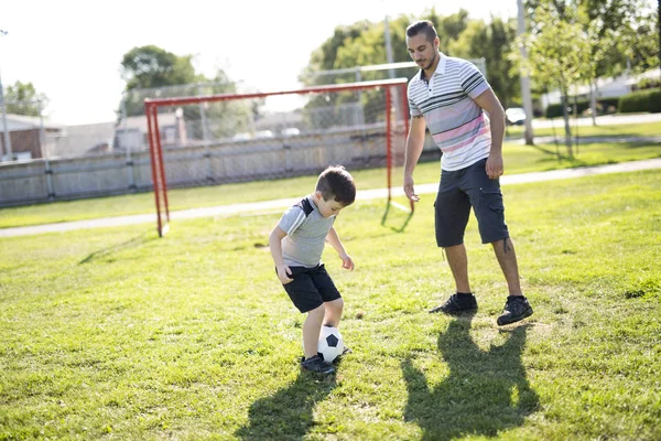 Man med barn som spelar fotboll på fältet — Stockfoto