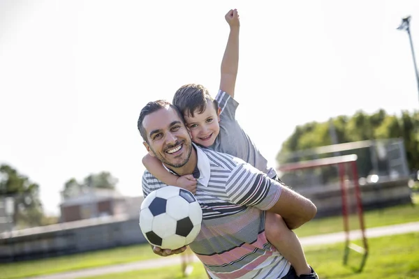 Man med barn som spelar fotboll på fältet — Stockfoto