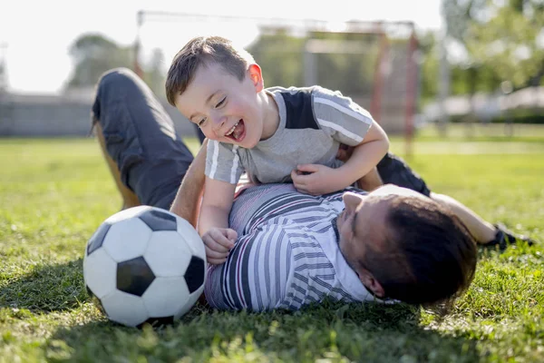 Man med barn som spelar fotboll på fältet — Stockfoto