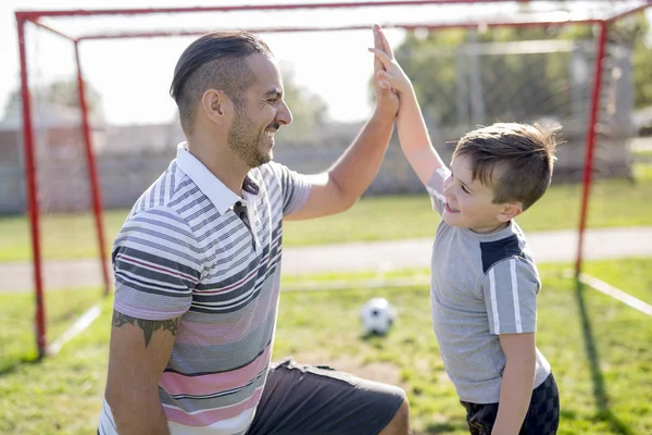 Man met kind voetballen op het veld — Stockfoto