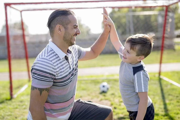 Man med barn som spelar fotboll på fältet — Stockfoto