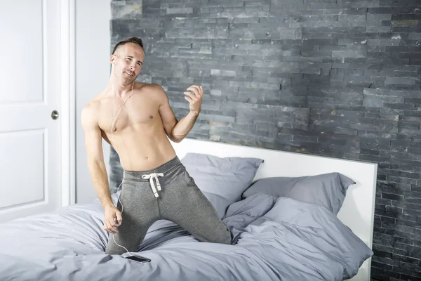 Young man in bed playing air guitar — Stock Photo, Image