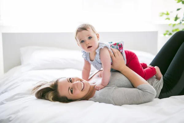 Pretty baby sit on mom in silk bed — Stock Photo, Image