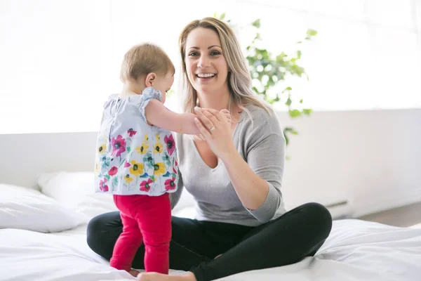 Bebê bonito sentar na mãe na cama de seda — Fotografia de Stock