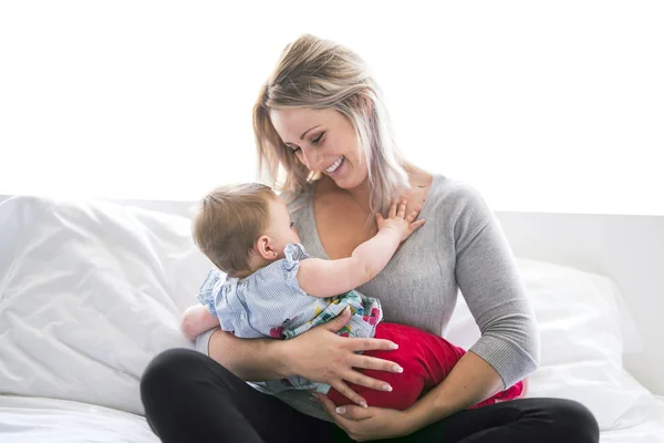 Bonito bebé sentarse en mamá en la cama de seda — Foto de Stock