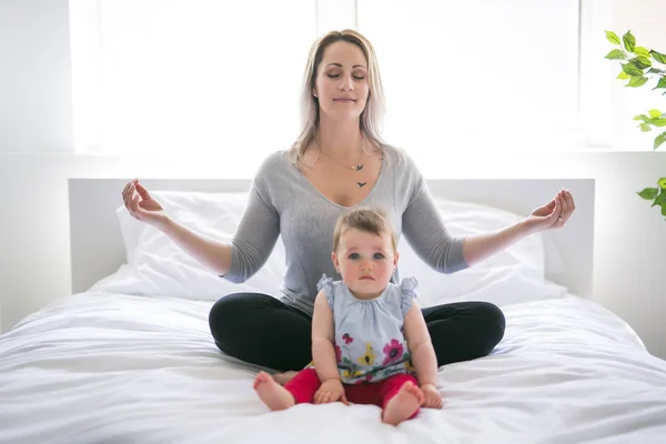 Bebê bonito sentar na mãe na cama de seda — Fotografia de Stock