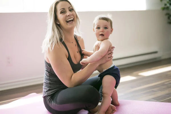 Jovem mãe faz exercícios de ioga físico junto com seu bebê — Fotografia de Stock