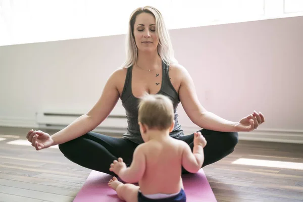 Jovem mãe faz exercícios de ioga físico junto com seu bebê — Fotografia de Stock
