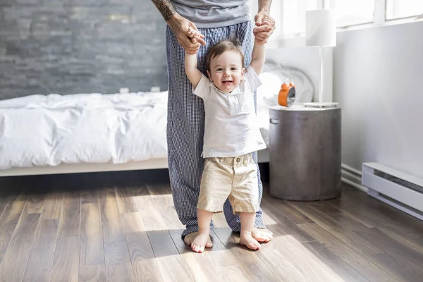 Padre che insegna a un bambino a camminare in camera da letto a casa — Foto Stock