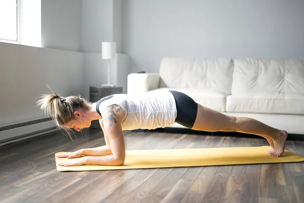 Retrato de comprimento total de atraente jovem mulher trabalhando em casa na sala de estar, fazendo ioga ou exercício pilates — Fotografia de Stock