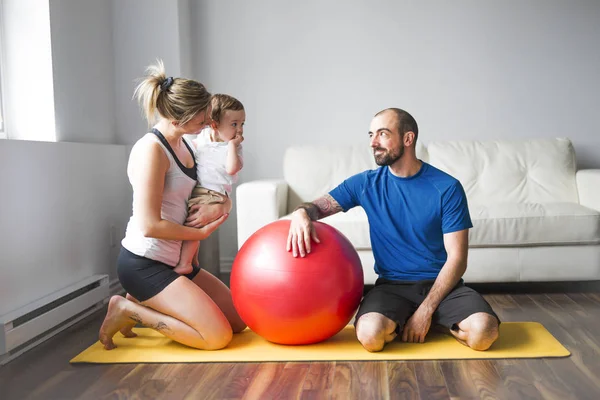 Sport familie houdt zich bezig met fitness en yoga met een baby thuis — Stockfoto